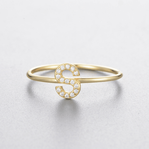 Gold bracelet with a letter 'S' design on a light gray background