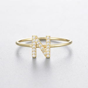 Gold ring with letter 'N' design on a light gray background