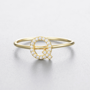 Gold ring with a letter 'Q' design on a light gray background