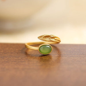 Gold ring with a green gemstone on a wooden surface