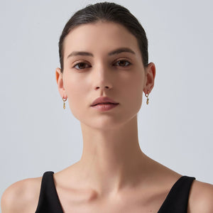 Woman wearing gold earrings against a plain background