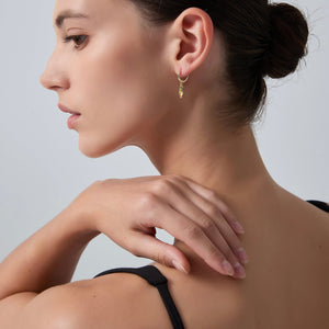Woman wearing a gold earring with a neutral background