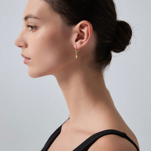 Woman wearing a gold earring on a plain background