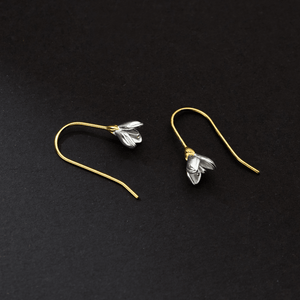 Pair of gold and silver floral earrings on a black background