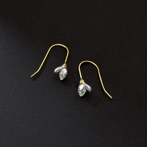 Pair of gold and silver floral earrings on a black background