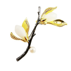 Jewelry brooch with gold leaves and a pearl on a white background