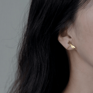 Gold dragonfly earring worn by a person with dark hair.