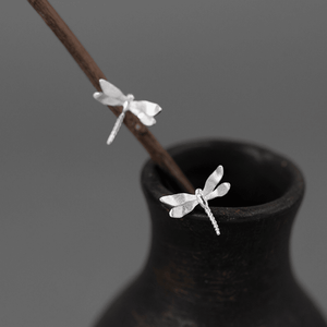 Silver dragonfly earrings on a dark vase with a gray background