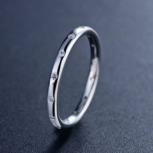 Silver ring with small diamonds on a dark gray background