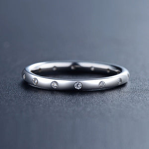 Silver ring with small diamonds on a dark gray background