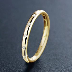 Gold ring with small diamonds on a dark gray background