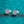 Pair of silver earrings with clear gemstones on a teal glittery background