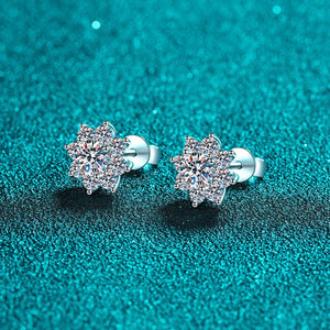 Pair of silver earrings with clear gemstones on a teal glittery background