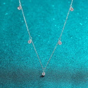 Silver necklace with small round pendants on a teal textured background