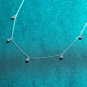 Silver necklace with small round pendants on a teal background