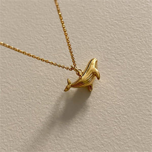 Two whale charm necklaces, one plated in silver and the other in gold, displayed against a neutral background.