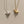 Gold and silver whale-shaped pendants on chains against a beige background