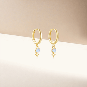 Gold hoop earrings with star-shaped opalite stones on a beige background