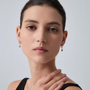 Close-up of a woman wearing gold earrings against a light gray background