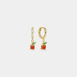 Gold hoop earrings with red apple charms on a light gray background