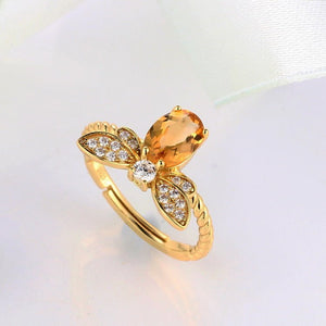 Gold butterfly ring with a yellow gemstone on a light background