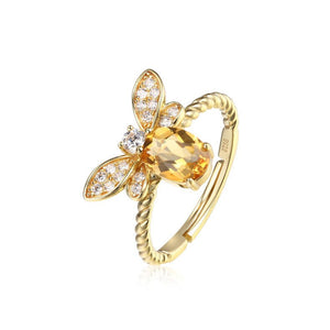 Gold butterfly ring with a central gemstone on a white background