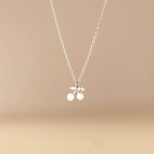 Necklace with cherry pendant on a beige background
