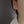 Close-up of an ear wearing a silver earring with a clear gemstone on a neutral background