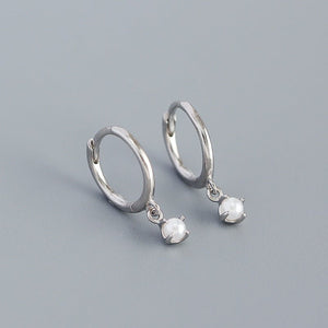 Silver hoop earrings with round gemstones on a gray background