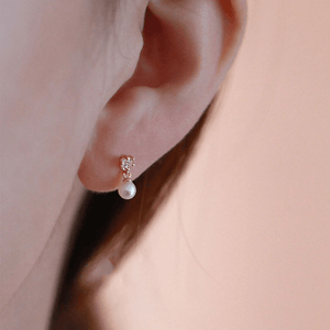 Pearl earring worn on an ear with a soft background