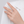 Hand wearing a ring with a pink gemstone on a white background