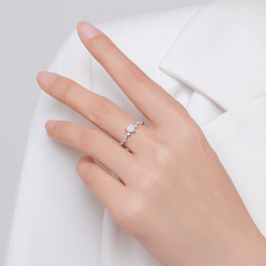 Hand wearing a ring with a pink gemstone on a white background