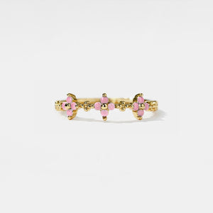 Gold ring with pink gemstones on a white background