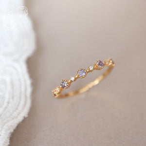Gold ring with small gemstones on a beige background