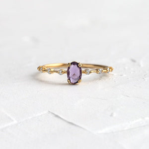 Gold ring with a purple gemstone on a white textured background