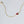 Gold necklace with a red heart-shaped gemstone on a light gray background