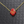 Red Hamsa hand pendant necklace on a gold chain against a textured gray background
