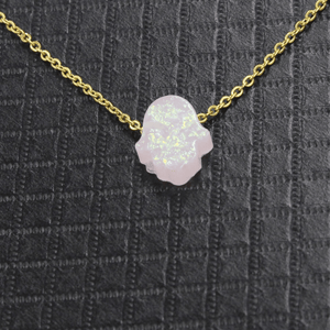 Necklace with a pink opal hamsa pendant on a textured black background