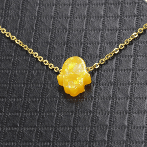 Yellow crystal pendant necklace on a textured gray background