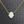 Necklace with a white opal hamsa pendant on a gold chain against a gray textured background