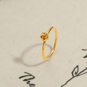 Gold ring with a rose design on a textured beige background