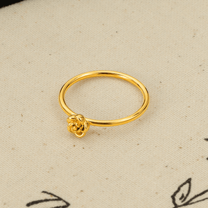 Gold ring with a small flower design on a beige background