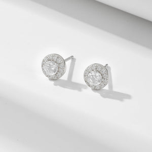 Pair of silver earrings with clear gemstones on a light gray background