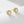 Gold earrings with clear gemstones on a light gray background