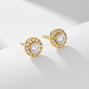 Gold earrings with clear gemstones on a light gray background