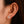 Close-up of an ear wearing a diamond stud earring with dark hair.