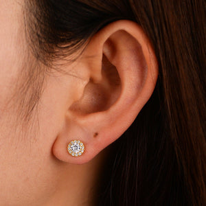 Close-up of an ear wearing a diamond stud earring with dark hair.
