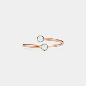 Rose gold bangle with opal stones on a light gray background