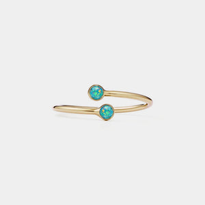 Gold bracelet with two turquoise stones on a light gray background