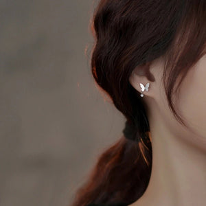 Butterfly earrings worn by a person with a blurred background